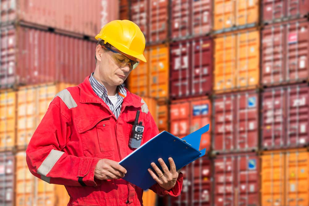 Man in hard hat standing in front of shipping containers