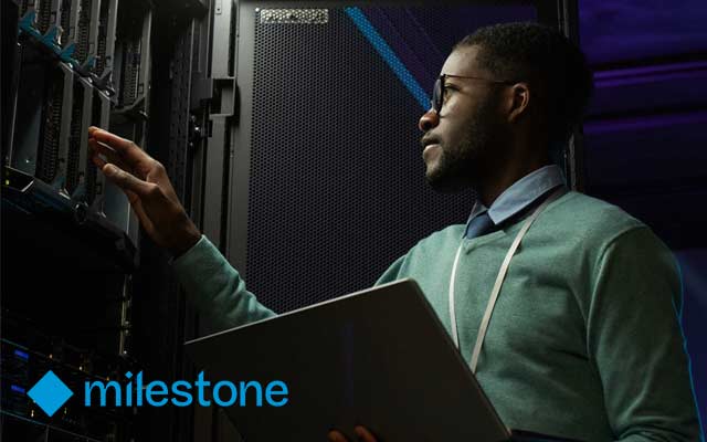 Man holds laptop in data centre. Milestone Systems logo.
